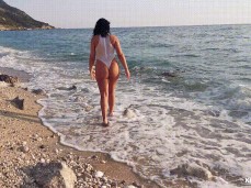 Kinky Eveline walks on beach in sheer one piece bikini gif